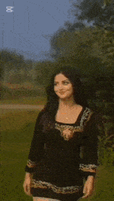 a woman in a black dress is standing in a field with the word lama on the bottom left