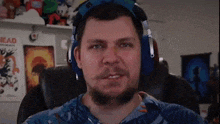 a man with a beard is wearing headphones and a blue shirt .