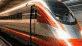 a red and silver train is going down the tracks .