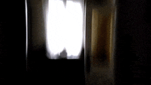 a dark room with a light shining through the curtains