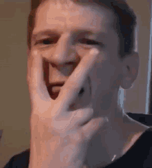 a man is covering his face with his hand and making a funny face .
