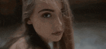 a close up of a woman 's face with hair blowing in the wind