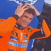 a man wearing an orange jacket with a dell logo on it is holding his head .