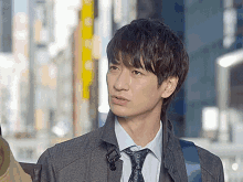 a man wearing a grey coat and tie looks to the side
