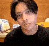 a young man in a black shirt looks at the camera