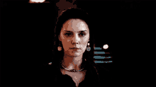 a woman wearing a choker necklace and earrings is looking at the camera