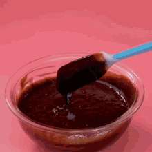 a bowl of chocolate sauce with a blue spatula