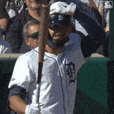 a man in a tigers jersey is holding a baseball bat