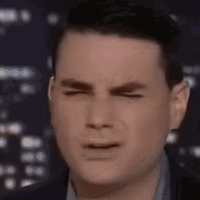 a man is making a funny face with his eyes closed and his mouth open .