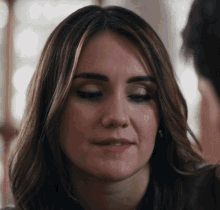 a close up of a woman 's face with a man in the background
