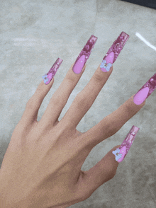 a close up of a woman 's hand with long pink nails with a butterfly design