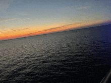 a sunset over a large body of water with a few lights in the distance