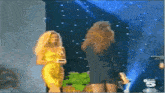 two women standing on a stage with the number 5 on the bottom