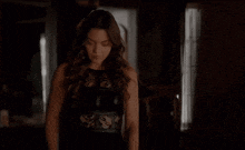 a woman in a black dress stands in front of a window in a dark room