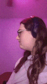 a woman wearing headphones and glasses against a pink background