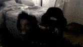 a person is laying on a bed in a dark room with a fan in the background