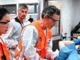 a man wearing an orange vest with a sticker that says ' emergency ' on it