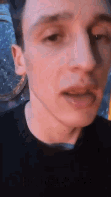 a close up of a man 's face with a black shirt on