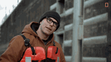 a man wearing a beanie and glasses is holding a life vest that says a2 on it