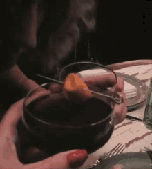 a person holding a glass of wine with an orange peel on a toothpick