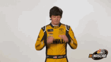 a man in a yellow and black dewalt racing suit wipes his face