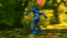 a blurry picture of a person in a blue suit running through the woods