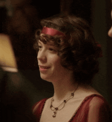 a woman is wearing a red dress and a necklace