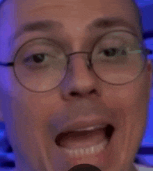 a close up of a man wearing glasses and smiling with his tongue out .