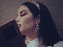 a woman wearing heart shaped earrings and a necklace with the letter g on it