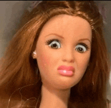 a close up of a barbie doll making a funny face with her mouth open .