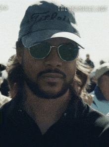 a man with a beard wearing a hat that says titleist on it