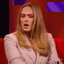 a woman sitting on a red couch with her mouth open and a purple background