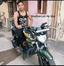 a man is sitting on a green motorcycle with the name madharcod hu mai written below him