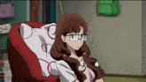 a girl with glasses is sitting in a chair with a pillow