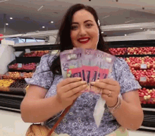 a woman in a blue shirt is holding up a bunch of 50 dollar bills