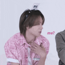a man wearing a pink plaid shirt has a sign on his head that says me