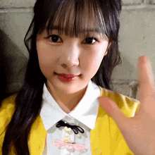 a girl wearing a yellow cardigan and a white shirt has her hand out