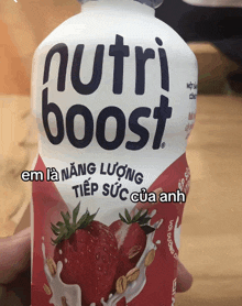 a person is holding a bottle of nutri boost strawberry flavored drink
