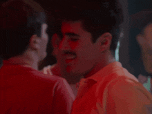 a man in a red shirt is kissing another man in a red shirt