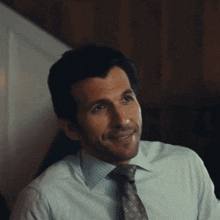 a man in a shirt and tie is smiling and looking to the side