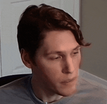 a close up of a man 's face with a gray shirt