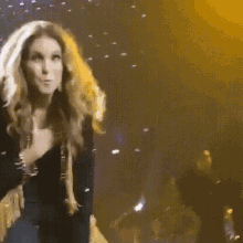 a woman singing into a microphone on a stage with a band in the background
