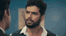 a man with a beard looks at another man in a suit