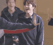 a man in a blue sweatshirt is giving a high five to another man