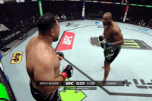 two men are fighting in a boxing ring with ufc logos on the floor