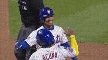 two mets baseball players wearing blue helmets are smiling