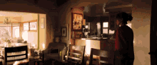 a woman in a red sweater is standing in a living room with a kitchen in the background