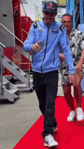 a man wearing a blue jacket and a red bull hat