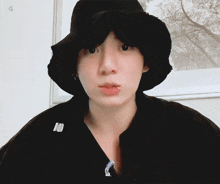a man wearing a black hat with a piercing in his lip looks at the camera