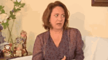 a woman is sitting on a couch in front of a table with dolls on it .